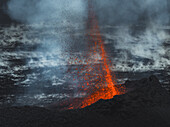 Luftaufnahme von feuriger Lava, die sich dramatisch von der dunklen, zerklüfteten Landschaft abhebt und einen starken Kontrast zur ätherischen, nebligen Kulisse bildet, Grindavik, Region Südliche Halbinsel, Island.