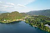 Luftaufnahme des ruhigen Sees, in dem sich die umliegenden grünen Hügel und malerischen Gebäude spiegeln, eine ruhige Szene, Bled, Radovljica, Slowenien.