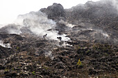 Chittagong, Bangladesh - 12 February 2024: View of workers amid the haze of burning waste in a vast landfill, a stark contrast of human labor against a backdrop of environmental concern.