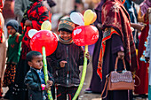 Bogura, Bangladesch - 03. November 2023: Blick auf Kinder inmitten einer lebhaften Menschenmenge, die bunte Luftballons halten, die sich von den gedämpften Tönen der traditionellen Gewänder abheben.