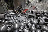 Keraniganj, Bangladesh - 27 December 2020: View of a craftsman amidst a sea of gleaming metal pots, shaping each piece with diligent hands in a workshop, blending tradition with labor.