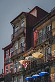 Porto, Portugal - 17. Juni 2022: Blick auf alte Gebäude mit bunten Fassaden und schmiedeeisernen Balkonen, die in Sonnenlicht getaucht sind.