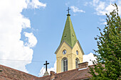 View of the Heilandskirche church tower rises with a green spire against a bright blue sky with fluffy clouds, a beacon of faith, Graz, Steiermark, Austria.
