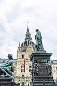 View of striking statues stand guard before the city hall, its spire piercing the sky, a flag adding a touch of color, Graz, Steiermark, Austria.