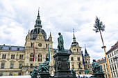 View of ornate statues stand guard before the Graz City Hall, flags fluttering in the breeze, under a vast sky, Graz, Steiermark, Austria.