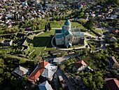 Aerial view of the Bagrati Cathedral stands majestically amidst verdant foliage and ancient ruins, a testament to time and faith, Kutaisi, Imereti, Georgia.