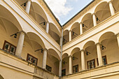 View of sun-drenched courtyard with elegant arches supported by columns, casting shadows on the walls in the inner structure, Graz, Austria.