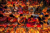 Dhaka, Bangladesh - 13 November 2018: View of devotees kneeling in prayer, surrounded by the warm glow of countless diyas, creating a scene of serene devotion.