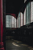 Porto, Portugal - 17 June 2022: View of a dimly lit interior, with sunlight filtering through the blinds, casting ethereal patterns on the floor.