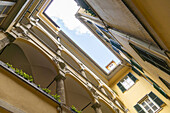 View of the sky framed by the ornate yellow architecture of a courtyard building, with arched openings and green accents, Graz, Austria.