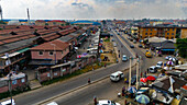 Luftaufnahme einer belebten Straße mit lebhaften Marktständen und Gebäuden, eine lebendige Szene von Handel und Gemeinschaft, Lagos, Nigeria.