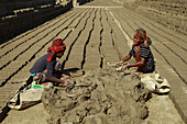Feni, Bangladesh - 26 November 2018: View of children immersed in labor, their small hands shaping mud into bricks amidst the vast, sun-baked brickyard.