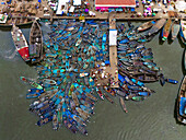 Aerial view of a bustling harbor filled with colorful boats clustering around a narrow pier under the sun, a vibrant scene of maritime activity, Port Harcourt, Rivers State, Nigeria.