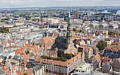 Aerial view of St. Peter's Church spire rises above the terracotta rooftops, a tapestry of history unfolding under a soft, diffused light, Riga, Latvia.