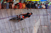 Chattogram, Bangladesh - 25 April 2019: View of a motorcyclist defying gravity on the 'Well of Death', a blur of motion against the wooden walls, under the watchful eyes of the crowd.