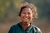 Dhangadhi, Nepal - 03 March 2023: View of a young girl's radiant smile, her eyes crinkling with joy, framed by the soft, blurred background of the Terai landscape.