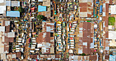 Aerial view of a bustling market with rusty rooftops and vibrant stalls, a dense network of activity unfolds below, Jos, Plateau, Nigeria.