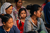 Dhangadhi, Nepal - 03 August 2023: View of a young girl amidst a group, her gaze intense, surrounded by muted tones and textures of the community.
