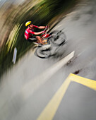 Paris, France - 27 July 2025: View of a cyclist speeding down the Tour de France route, a blur of motion against the grey asphalt and bright yellow road markings.