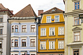 Blick auf lebendige Gebäude mit Terrakotta-Dächern und bunten Fassaden, die einen auffälligen Kontrast zum Himmel am Hauptplatz in Graz, Österreich, bilden.