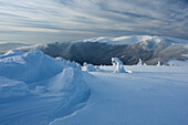 View of pristine, snow-laden peaks and valleys stretch under a vast sky streaked with wispy clouds, a cold, crisp landscape, Velka Fatra mountains, Belá-Dulice, Žilina Region, Slovakia.