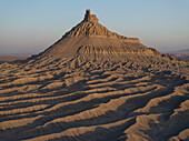 Aerial view of the stark, arid landscape where Factory Butte rises with dramatic lines and shadows in the Utah desert, Caineville, Utah, United States.
