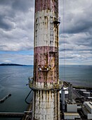 Luftaufnahme der Poolbeg Chimneys, eines markanten industriellen Wahrzeichens vor der Bucht von Dublin, mit leuchtenden roten und weißen Streifen, die mit der verwitterten Struktur kontrastieren, Dublin, County Dublin, Irland.