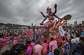Mumbai, India - 06 September 2025: View of a vibrant Ganesh Chaturthi immersion at Girgaum Chowpatty, with devotees in pink hues amidst a swirling cascade of water and faith.