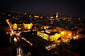 Aerial view of the Croatian National Theatre illuminated in bright yellow hues against the dark sky, traffic flowing around its perimeter, Zagreb, Zagreb, Croatia.