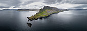 Aerial panoramic view of jagged cliffs meet the dark, rippled sea under a dramatic sky, painting a landscape of stark beauty in the Westfjords, Iceland.