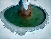 Aerial view of the Forggensee's icy embrace, where emerald waters meet stark white snow under a winter sky, Forggensee, Füssen, Germany.