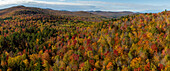 Luftaufnahme eines Panoramabildes, das die sanften Hügel und Wälder in warme Rot-, Orange- und Gelbtöne taucht. Sugar Hill, White Mountains, New Hampshire, Vereinigte Staaten.
