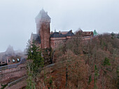 Aerial view of the imposing Château du Haut-Kœnigsbourg shrouded in a mystical fog, its ancient stones whispering tales of centuries past, Orschwiller, Castle Haut-Koenigsbourg, France.