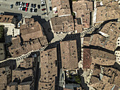 Aerial view of the ancient town's terracotta rooftops, punctuated by a distinctive arrow-marked pathway, casting shadows on the sunlit square, Pescocostanzo, Abruzzo, Italy.