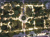 Aerial view of a vibrant park illuminated with warm lights, surrounded by lush trees and city streets, Kutaisi, Imereti, Georgia.