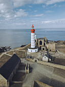 Aerial view of the Pointe Saint-Mathieu Lighthouse with its red top piercing the skyline amidst ancient stone ruins and the endless sea, Plougonvelin, Bretagne, France.