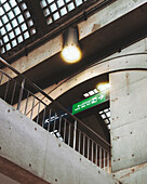 Uji, Japan - 21 February 2025: View of the Uji Station's interior, where the concrete pillars stand in stark contrast to the bright green directional sign and the soft glow of the overhead lights.