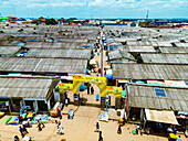 Luftaufnahme der belebten, mit Wellblechdächern gesäumten Marktstraßen unter dem hellen Himmel, eine pulsierende Szene von Handel und Gemeinschaft, Tudun Wada, Kaduna, Nigeria.