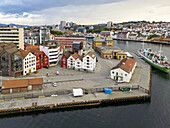 Luftaufnahme der farbenfrohen Gebäude am Hafen, wo das grüne Schiff mit den roten und weißen Fassaden kontrastiert und eine lebendige Szene am Wasser schafft, Stavanger, Rogaland, Norwegen.