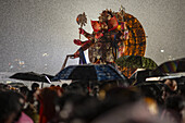 Mumbai, India - 06 September 2025: View of a vibrant Ganesh idol, adorned with gold, amidst a sea of umbrellas during heavy rain, a spectacle of faith and devotion.