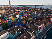 Aerial view of vibrant houses with multi-colored facades and terracotta roofs create a dazzling mosaic across the island, seen from above, Burano, Veneto, Italy.