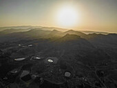Aerial view of the sun casting a golden glow over the rugged mountain peaks and calm lakes, Aaqoura, Mount Lebanon Governorate, Lebanon.