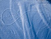 Aerial view of a large infinity symbol etched into the snow-covered landscape, creating a stark contrast between the white expanse and the defined lines, Füssen, Bavaria, Germany.