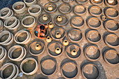 Bogura, Bangladesh - 22 October 2019: Aerial view of a craftsman immersed in the repetitive, earthy rhythm of pottery, surrounded by rings and pots, creating a textured tableau of tradition and skill.