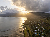 Aerial view of beautiful sunset over tranquil coastline with mountain backdrop and serene ocean, Le Morne, Riviere Noire, Mauritius.