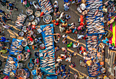 Bogura, Bangladesh - 18 November 2021: Aerial view of a bustling fish market, vibrant with activity as vendors display their fresh catches on blue tarps, surrounded by a dense crowd of shoppers..
