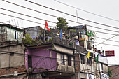 Chattogram, Bangladesh - 08 October 2022: View of vibrant buildings adorned with flags, a rooftop gathering buzzing with anticipation under a muted sky.