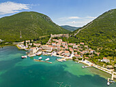 Luftaufnahme eines malerischen Küstendorfs, eingebettet in die schützende Umarmung alter Steinmauern und üppig grüner Hügel, Mali Ston, Gespanschaft Dubrovnik-Neretva, Kroatien.