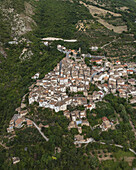Luftaufnahme eines malerischen Dorfes inmitten üppig grüner Hügel, Terrakotta-Dächer, die im Sonnenlicht glitzern, eine harmonische Mischung aus Natur und Architektur, Anversa degli Abruzzi, Abruzzen, Italien.