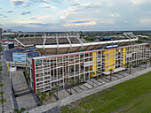 Orlando, United States - 21 July 2025: Aerial view of Camping World Stadium basks in the fading sunlight, its vibrant yellow and red accents popping against the muted green of the surrounding fields.